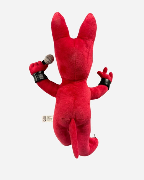 The 2025 Anime Plush Dog is a red plush toy with pointy ears, black wristbands, and a tail, holding a microphone in its right hand. The toy is displayed from the back against a plain white background.