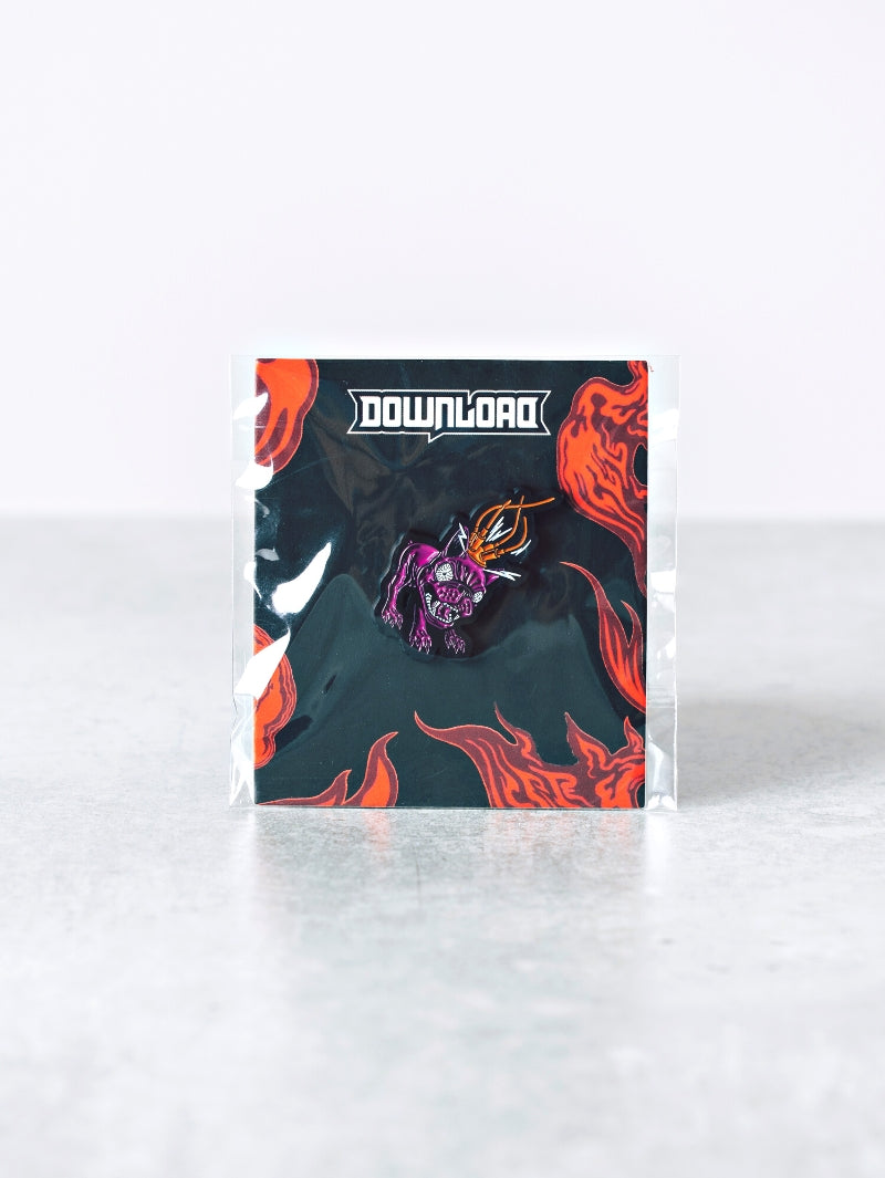 Download Festival enamel pin featuring a stylised purple dog wearing a spiked helmet with fiery orange detailing, mounted on a black backing card with red flames and the white Download logo at the top.