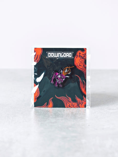 Download Festival enamel pin featuring a stylised purple dog wearing a spiked helmet with fiery orange detailing, mounted on a black backing card with red flames and the white Download logo at the top.