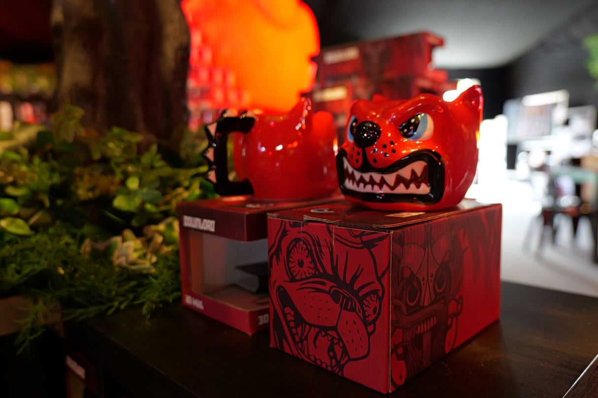 A fierce-looking ceramic Dog Head Shaped Mug by Download 2026 sits on a box with matching artwork, surrounded by greenery and a vibrant, colorful background.