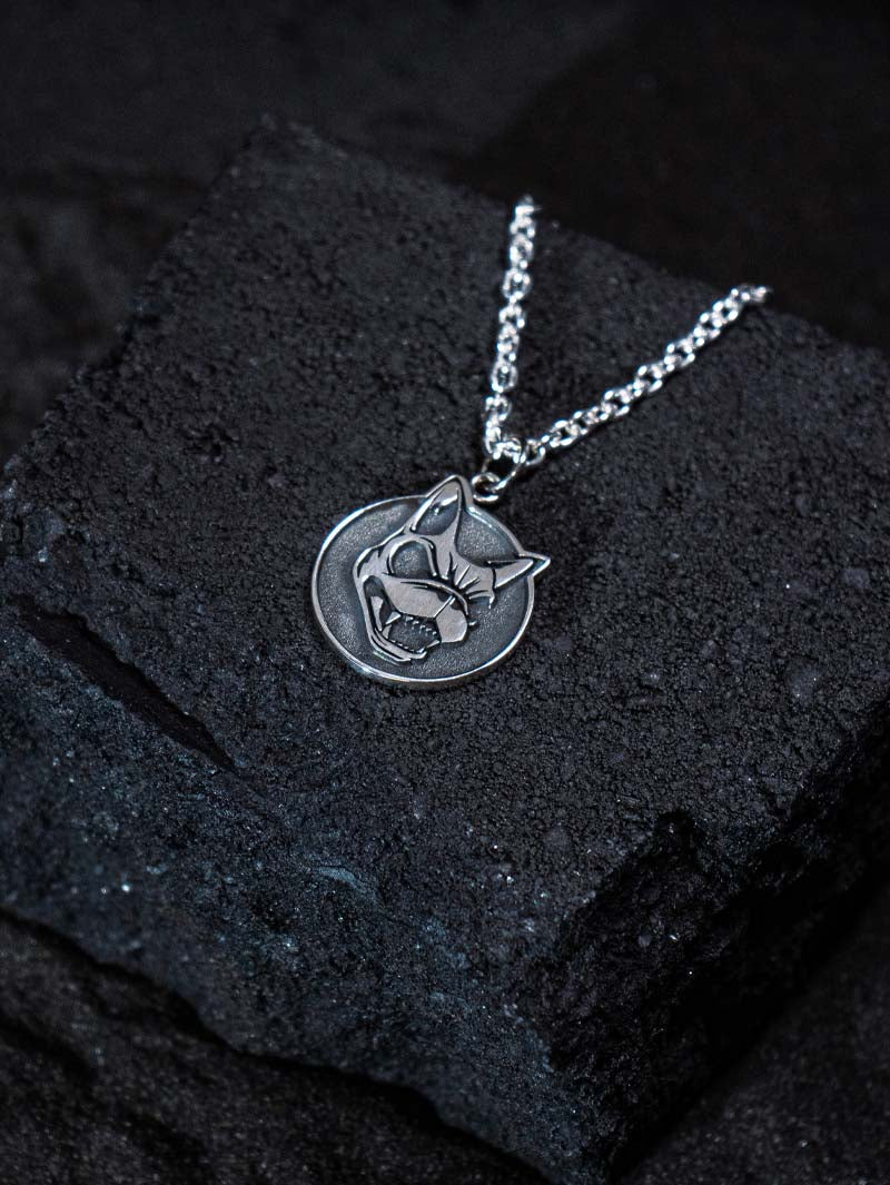 Close-up of the Download x ParabellumLDN sterling silver pendant necklace, featuring a snarling dog head design on a circular charm, shown on a black background.