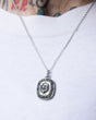A close-up of a person wearing the TGF x Download Necklace by Download 2026 over a white shirt, with tattooed skin visible above the collar.