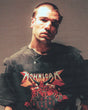 A man with short hair wears the 2026 P&Co Line Up T Shirt and layered necklaces, looking seriously at the camera. The image features a glitch effect with horizontal distortion lines.