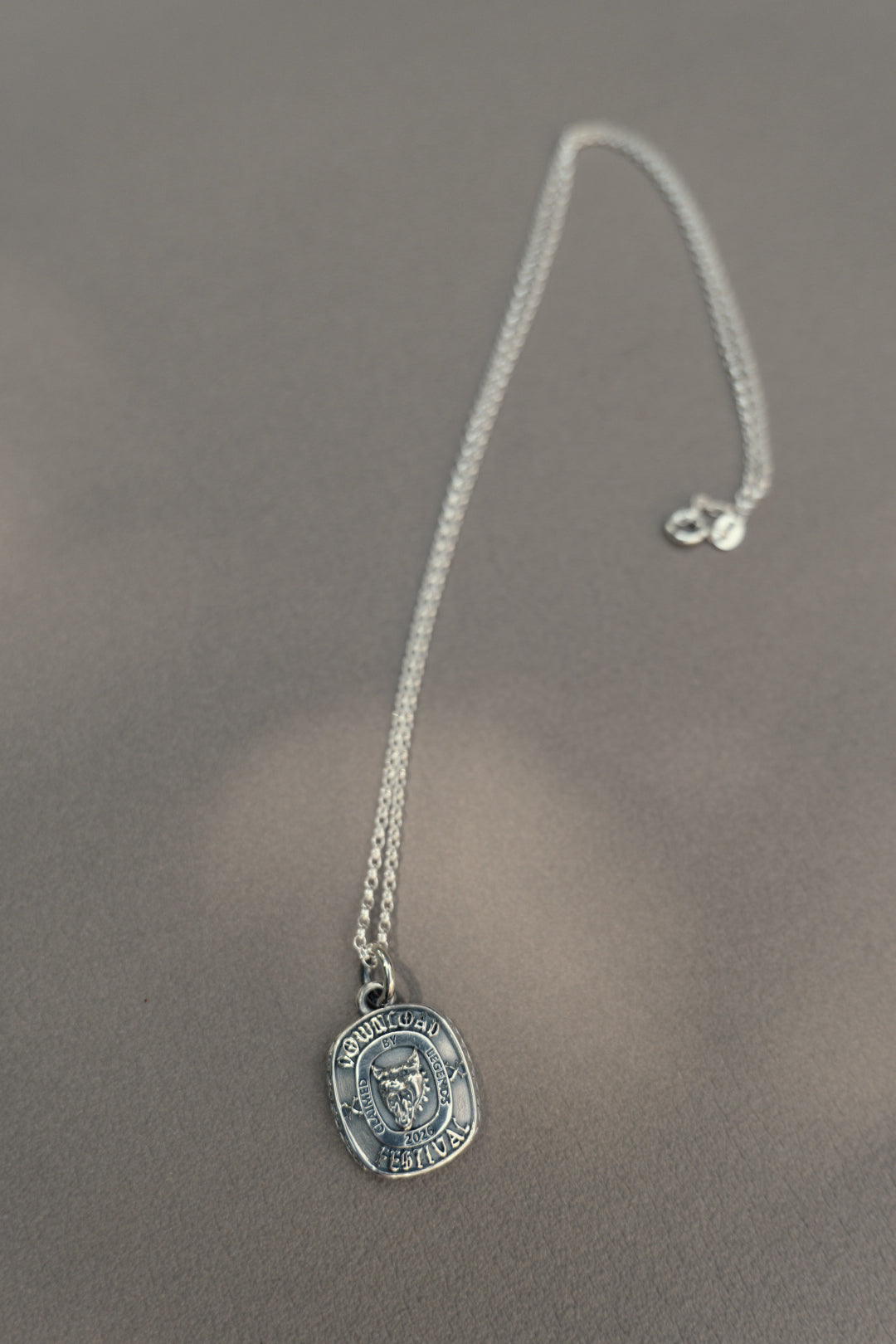 The TGF x Download Necklace by Download 2026 features a silver round pendant engraved with an owl and the phrase "Knowledge is Power," displayed on a soft, neutral surface.