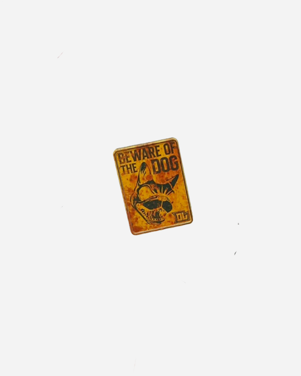The Pin Badge by Download 2026 is a small, rectangular yellow accessory featuring a dog's head illustration and the text "BEWARE OF THE DOG," shown against a plain white background.